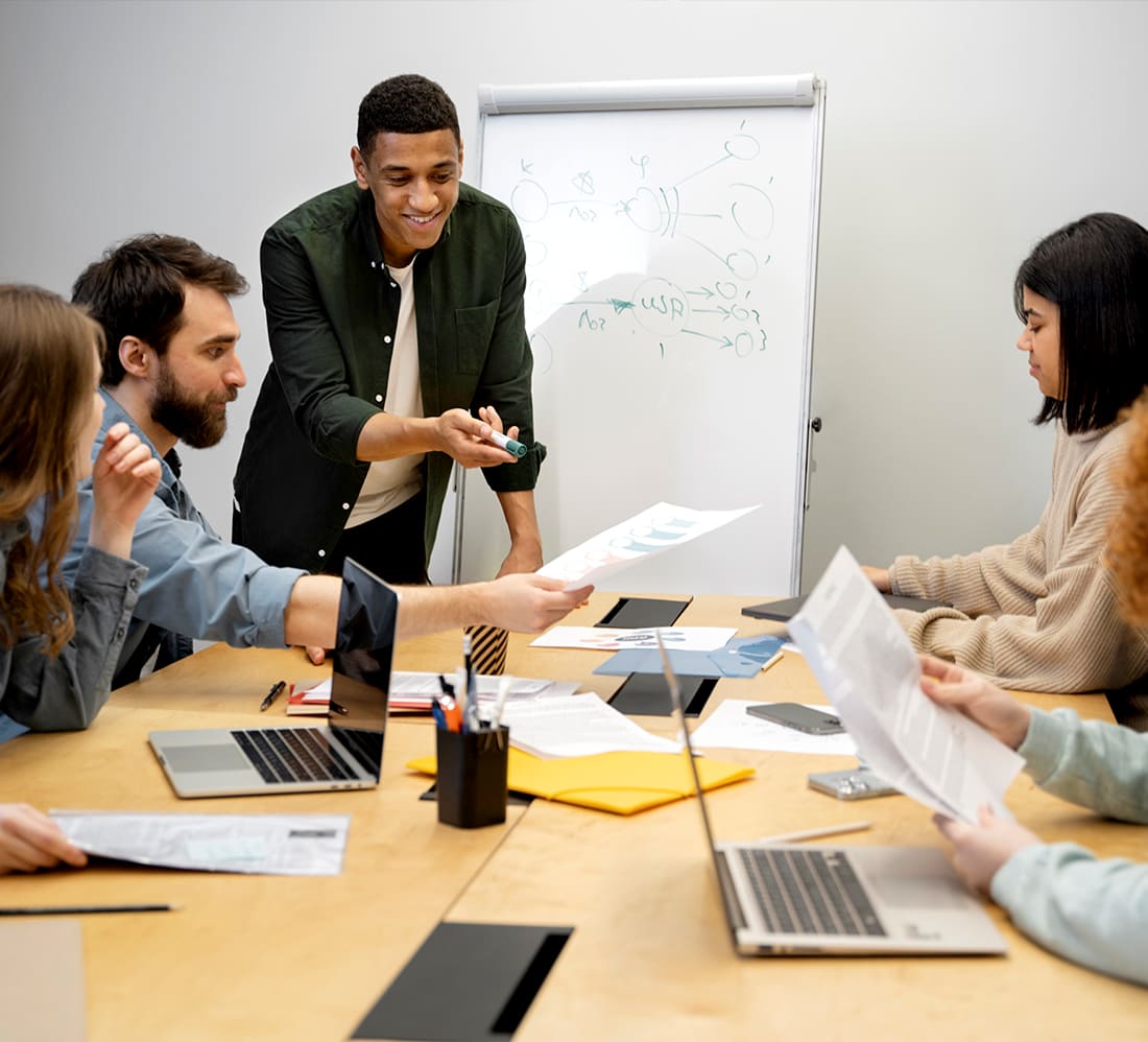 Diverse team brainstorming digital marketing strategies discussing charts on whiteboard.